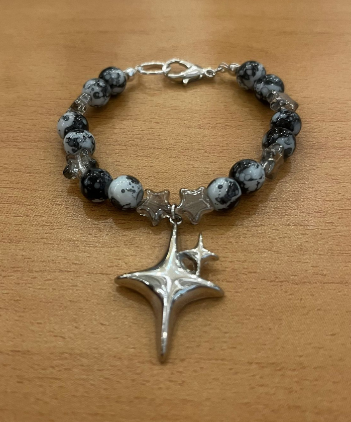 Bracelet with star-shaped silver pendant on a wooden surface